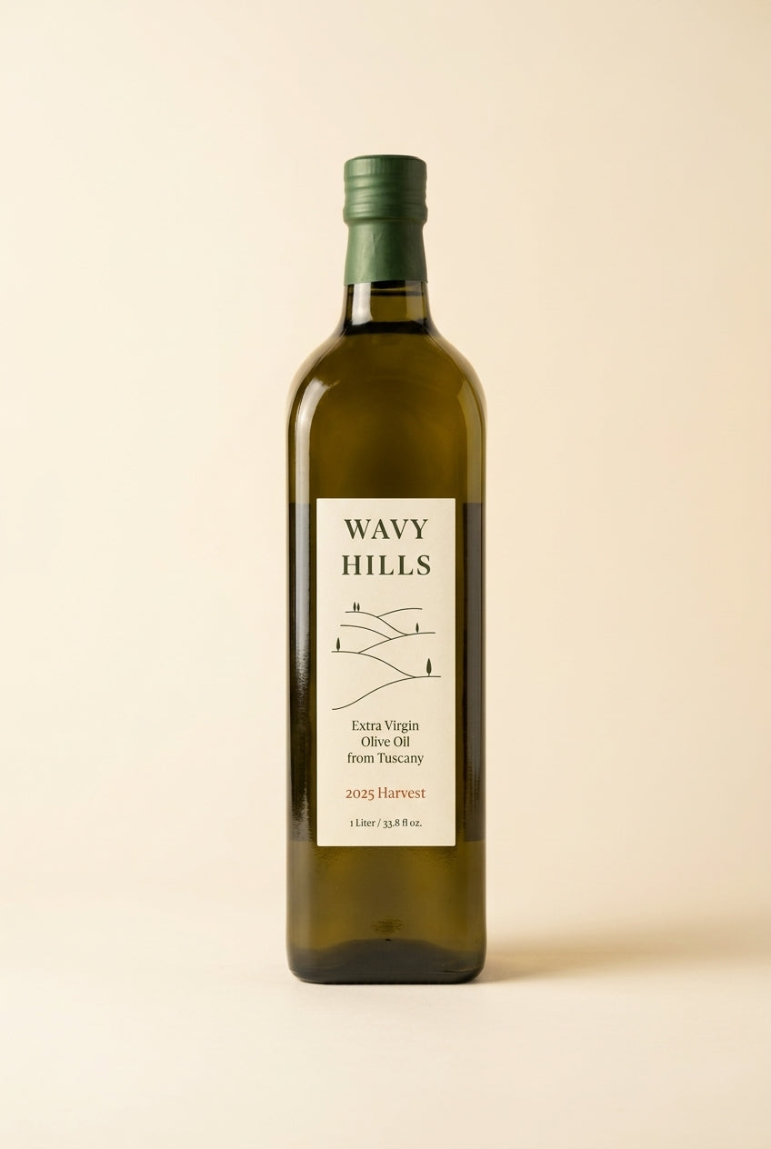 A bottle of Wavy Hills Extra Virgin Olive Oil with a dark green cap and a cream-colored label, set against a solid light beige background.
