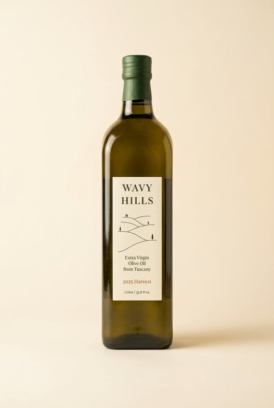 A bottle of Wavy Hills Extra Virgin Olive Oil with a dark green cap and a cream-colored label, set against a solid light beige background.